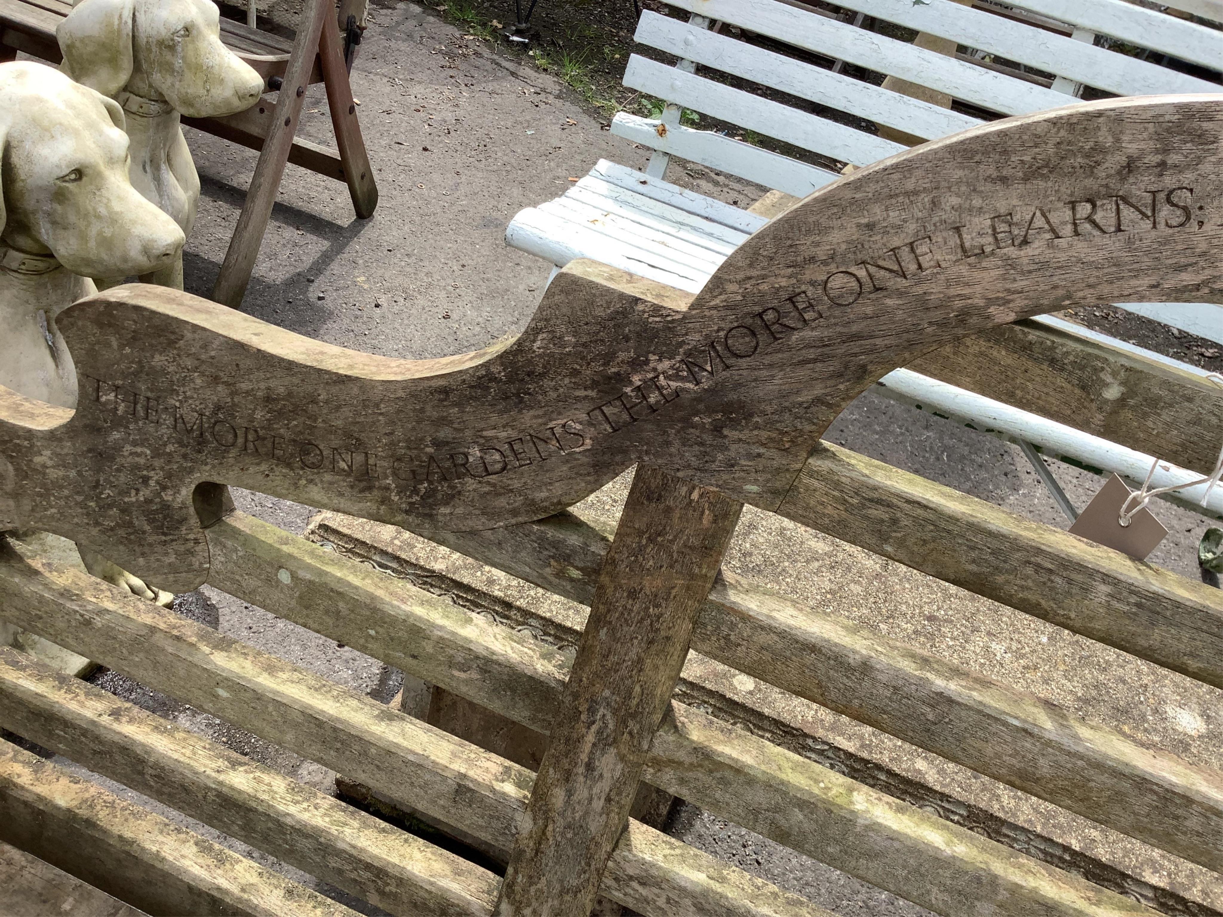 A weathered teak Lutyens style garden bench, with carved inscription, width 55cm, height 106cm